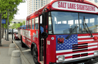 Red sightseeing bus parked by downtown street curb