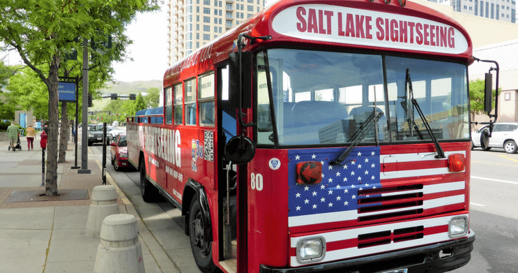 Red sightseeing bus parked by downtown street curb