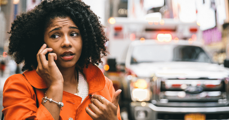 Concerned woman on phone with traffic in the background